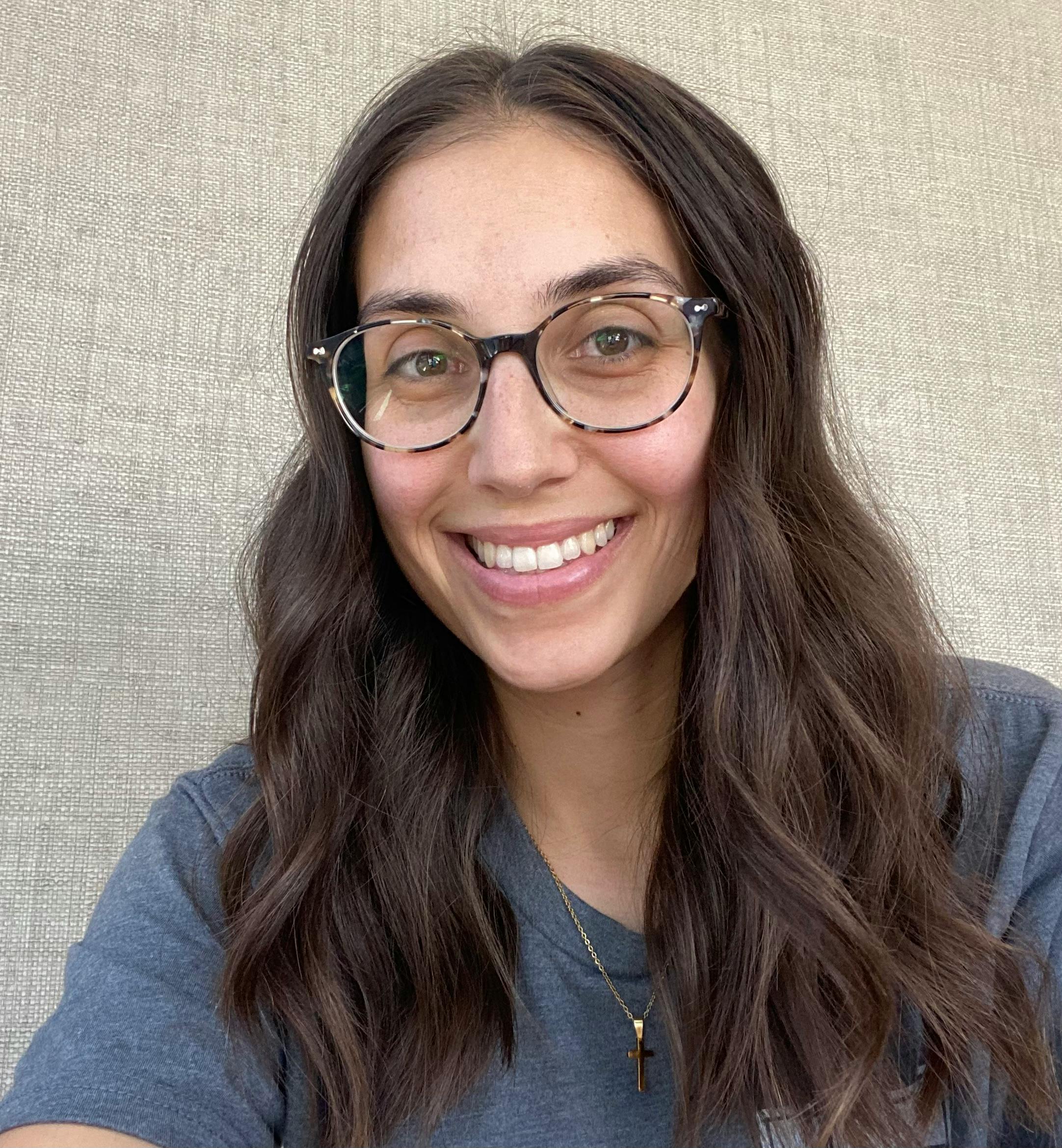 Person with long hair and glasses smiling
