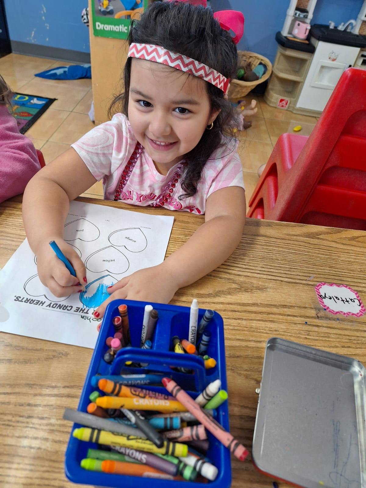 Child coloring a heart on paper with crayons