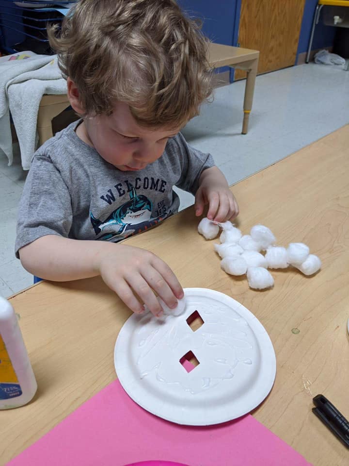 Child placing cotton balls on a paper plate