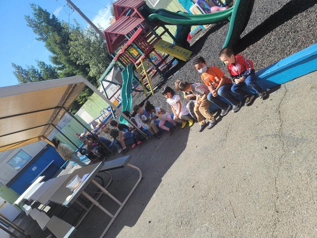Children sitting on a low wall next to a playground
