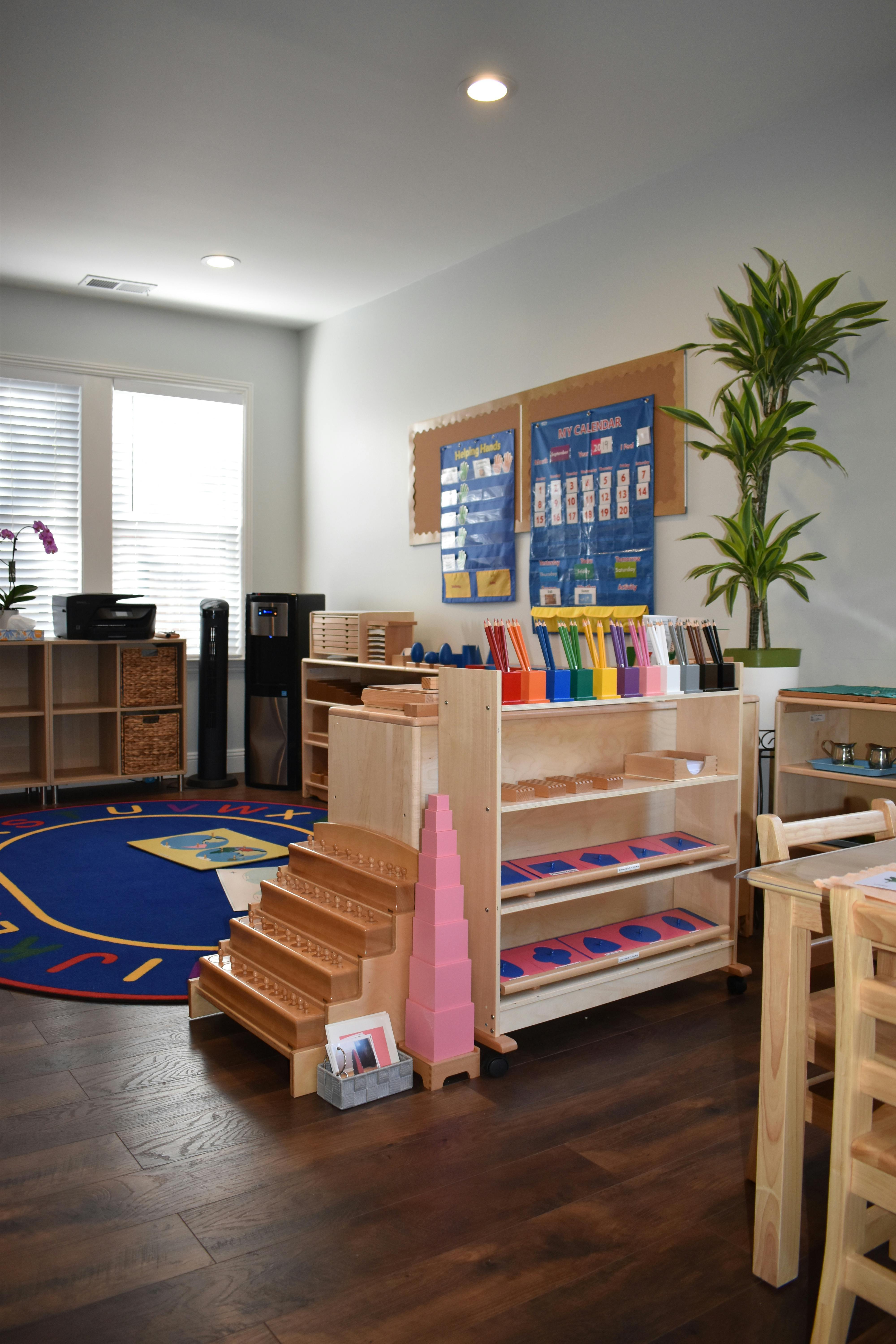 Montessori classroom with wooden shelves, learning materials, and a blue rug
