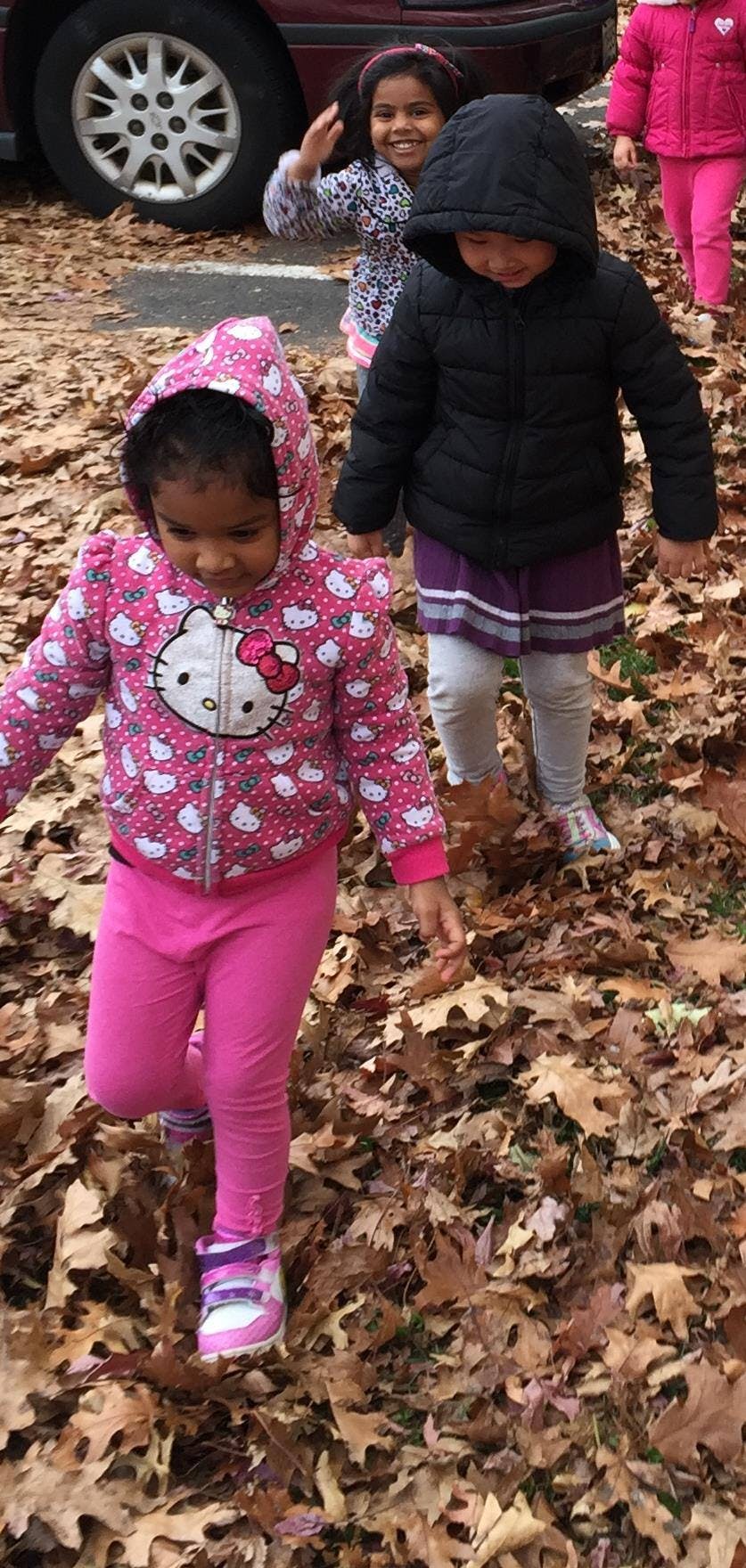 Children walking through fallen leaves