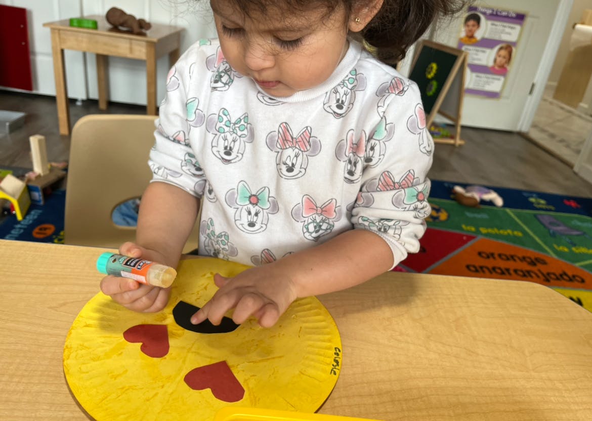 Child holding a glue stick and working on a craft project