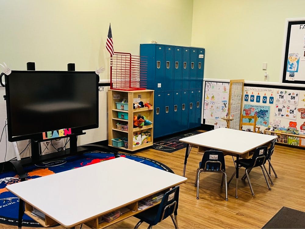 Classroom with tables, chairs, lockers, and an interactive display with the word "LEARN"