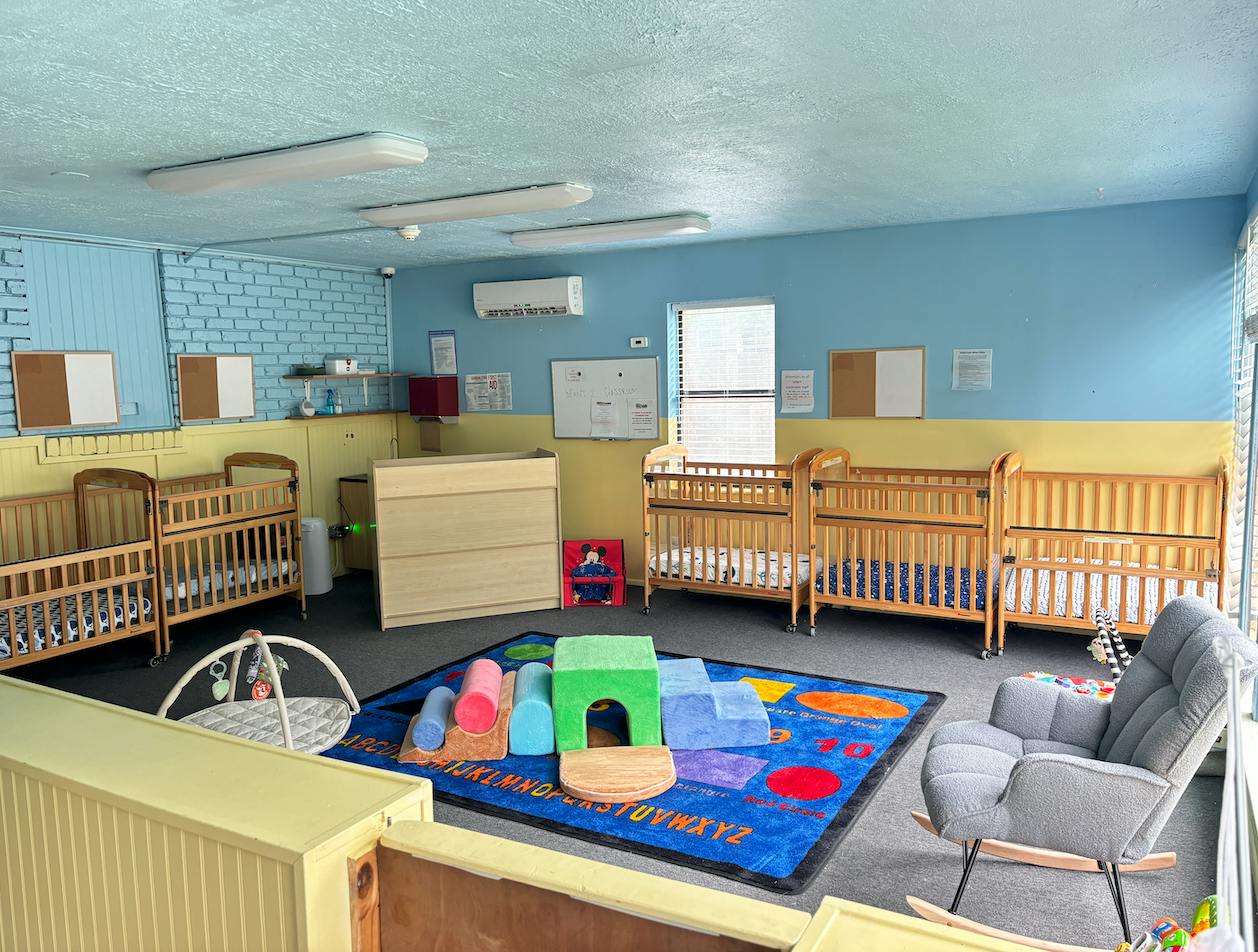 Cribs and soft play equipment inside a childcare classroom
