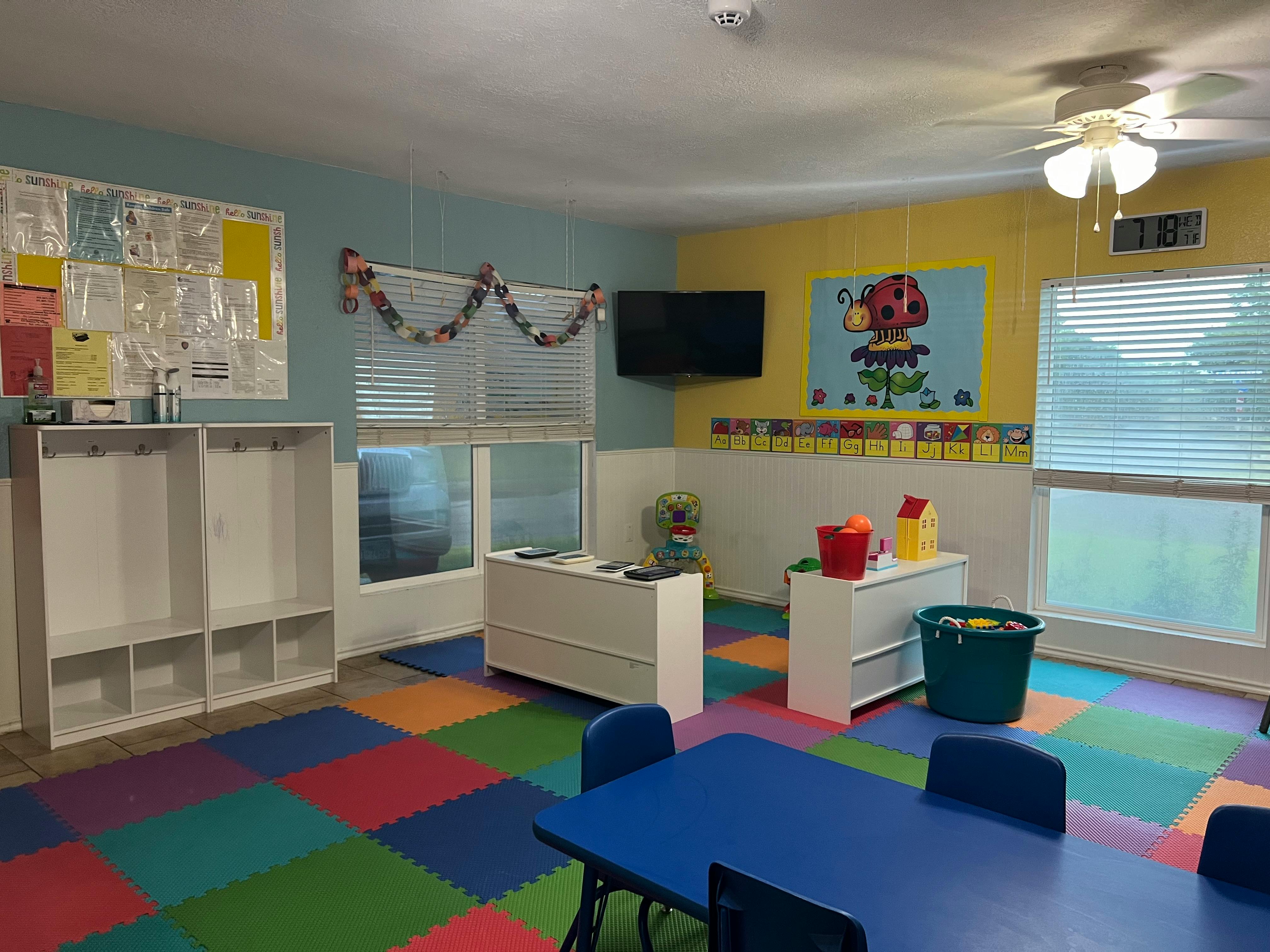 Classroom with colorful floor mats, tables, and storage units