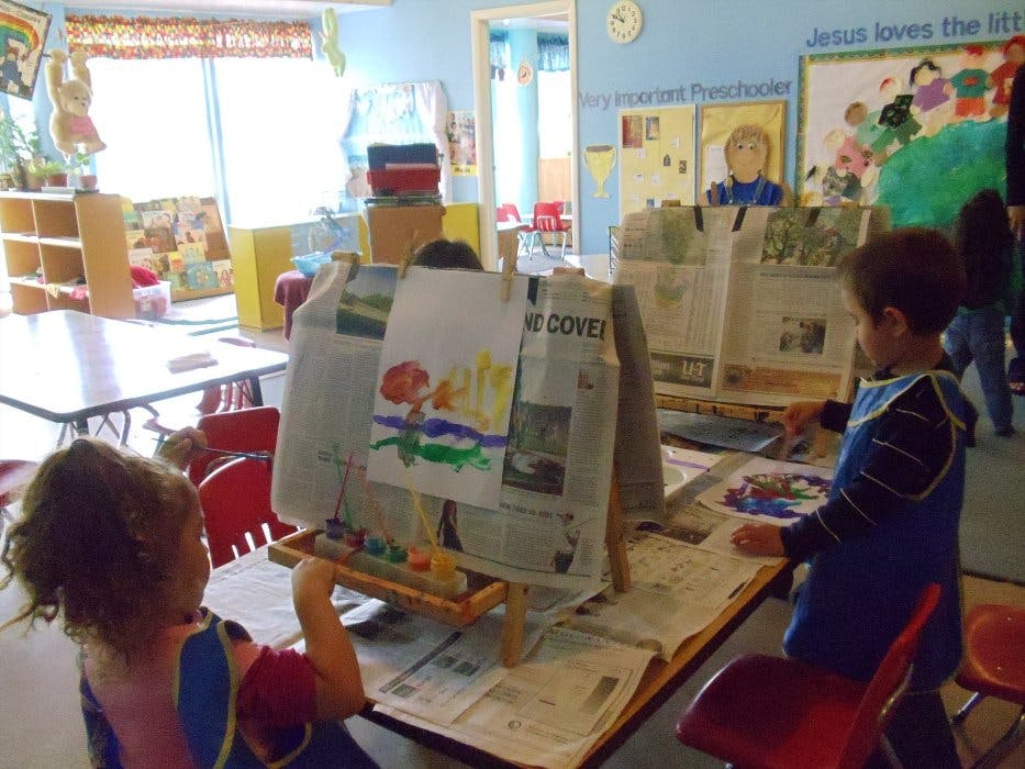 Two children painting at easels in a classroom