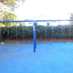 Empty swing set on a blue playground surface