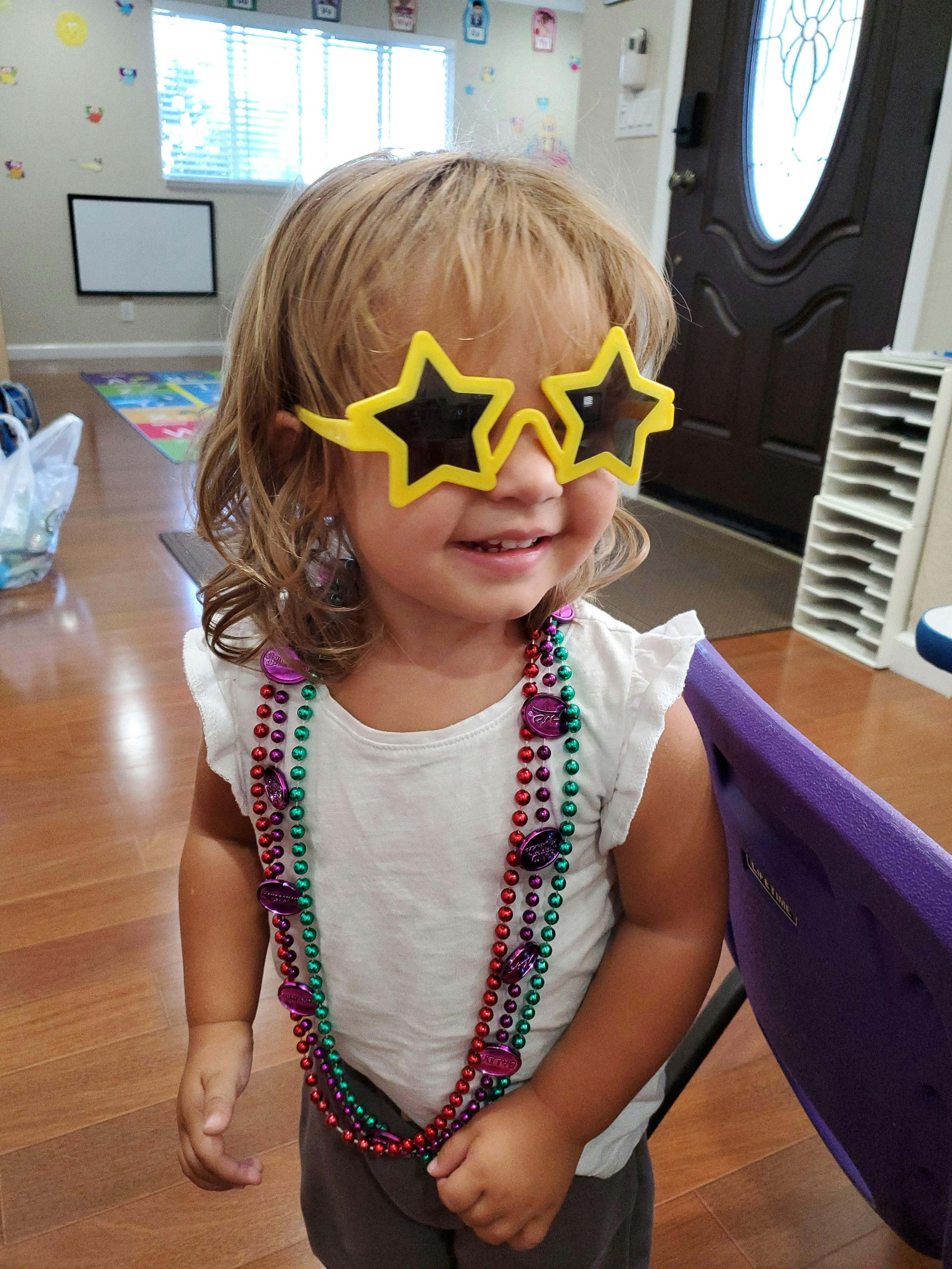 Child wearing star-shaped glasses and multiple beaded necklaces