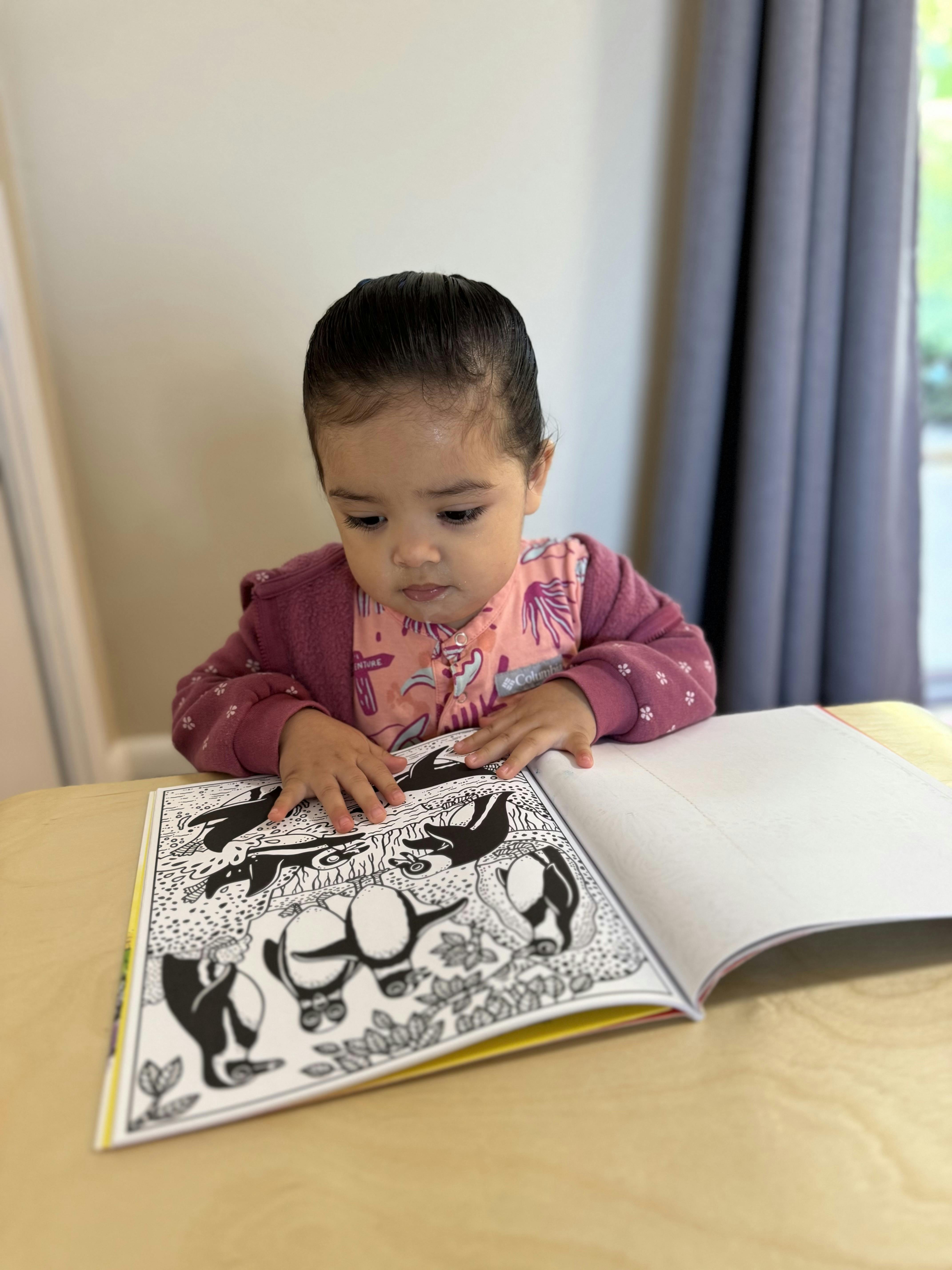 Child looking at an open coloring book on a table