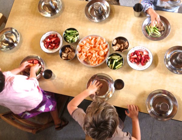 Children and an adult preparing food at a table