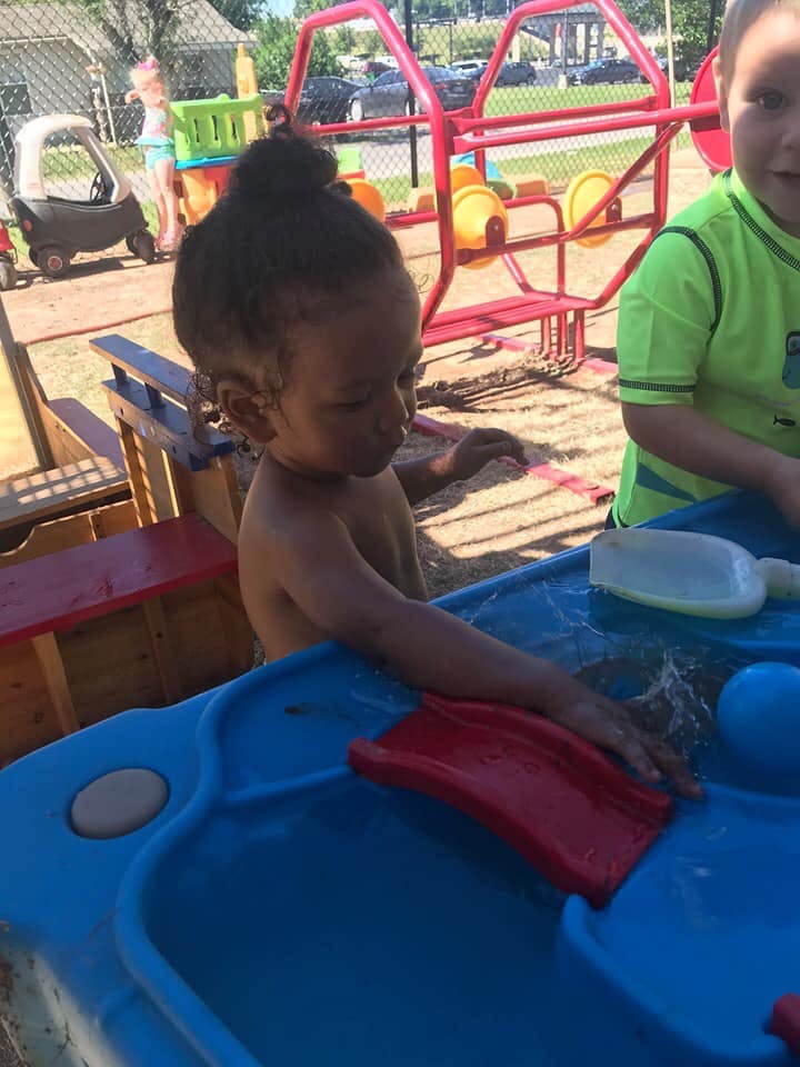Child playing with water in a blue water table