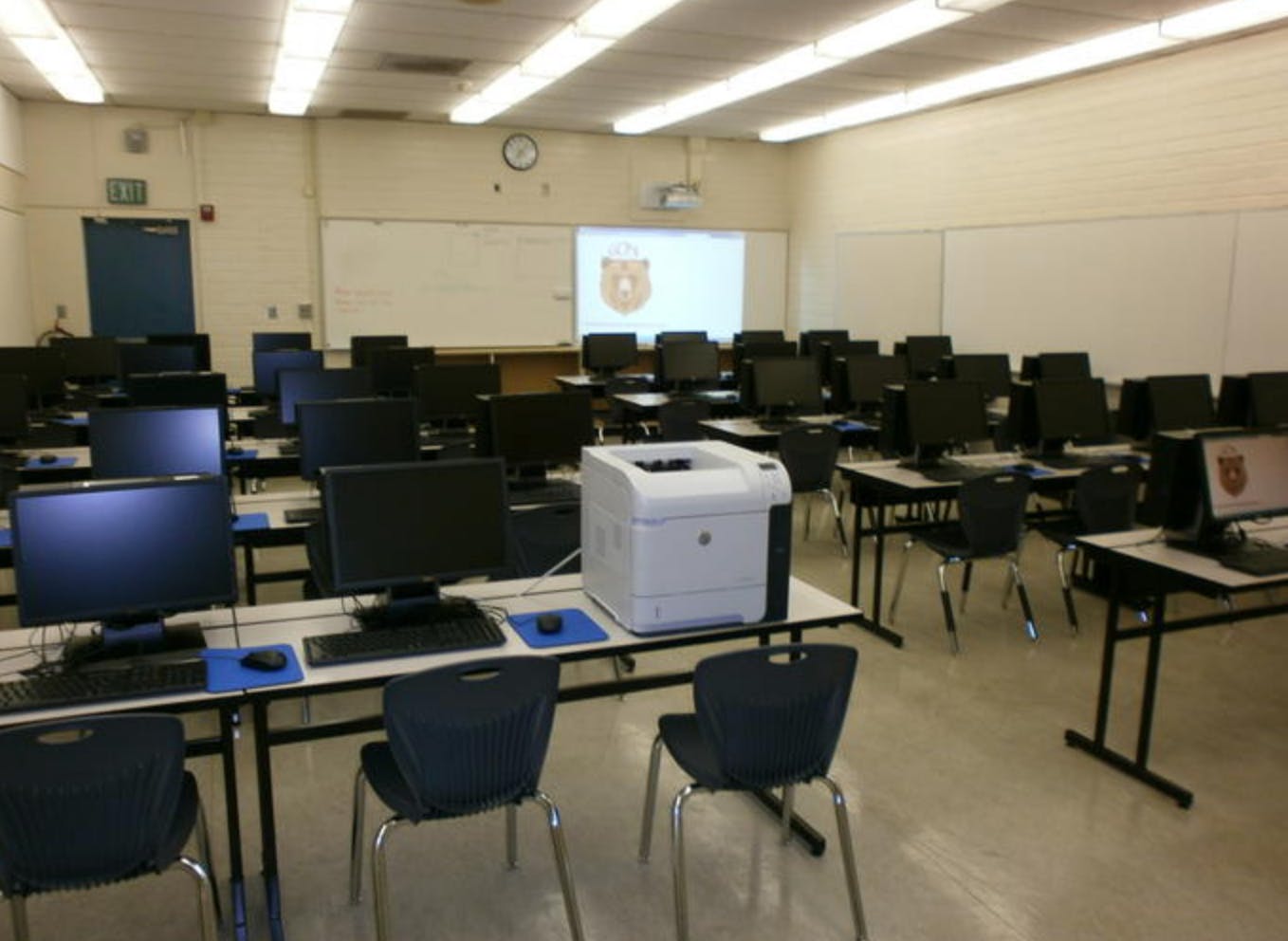 Computer lab classroom with rows of desks, monitors, and a printer