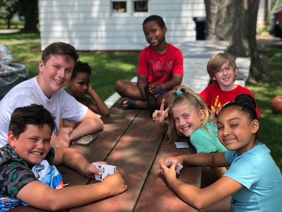 Group of children and teens playing cards at a picnic table