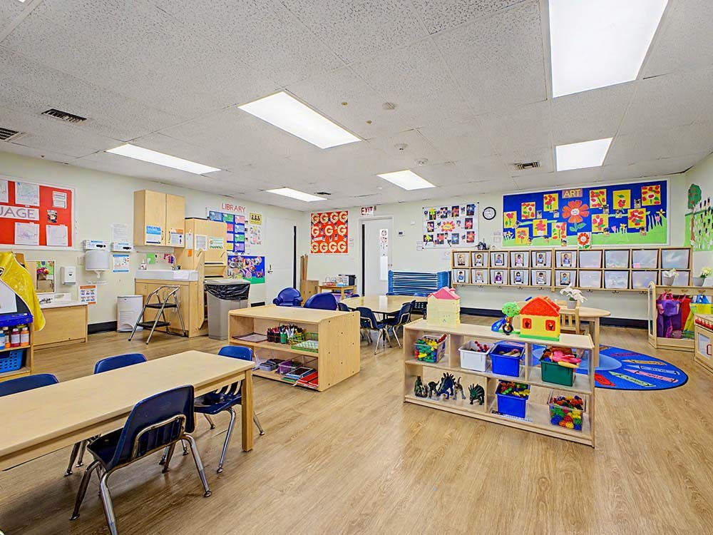 Classroom with tables, chairs, bookshelves, and art on the walls