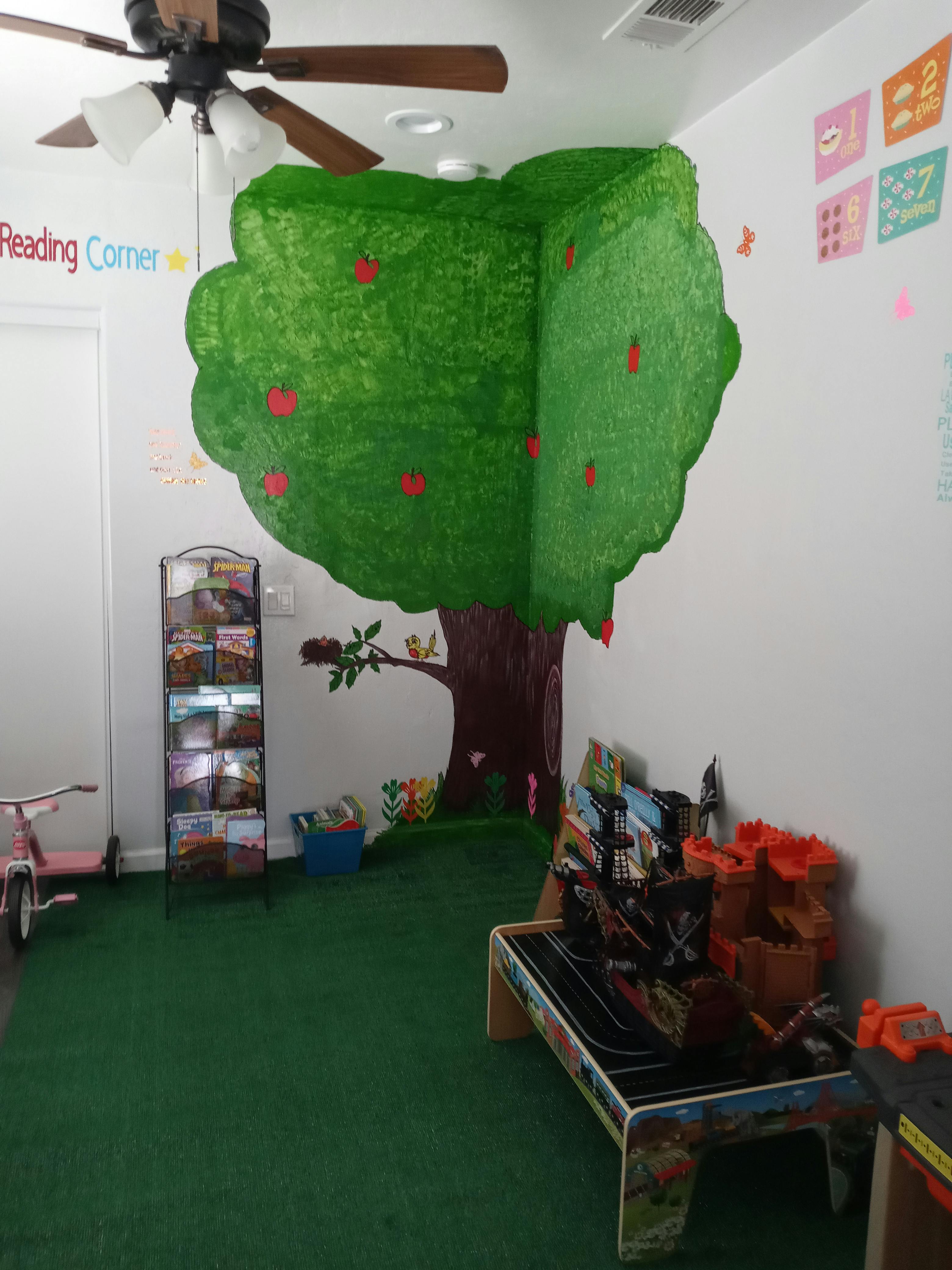 Playroom with a tree mural, green carpet, and toys