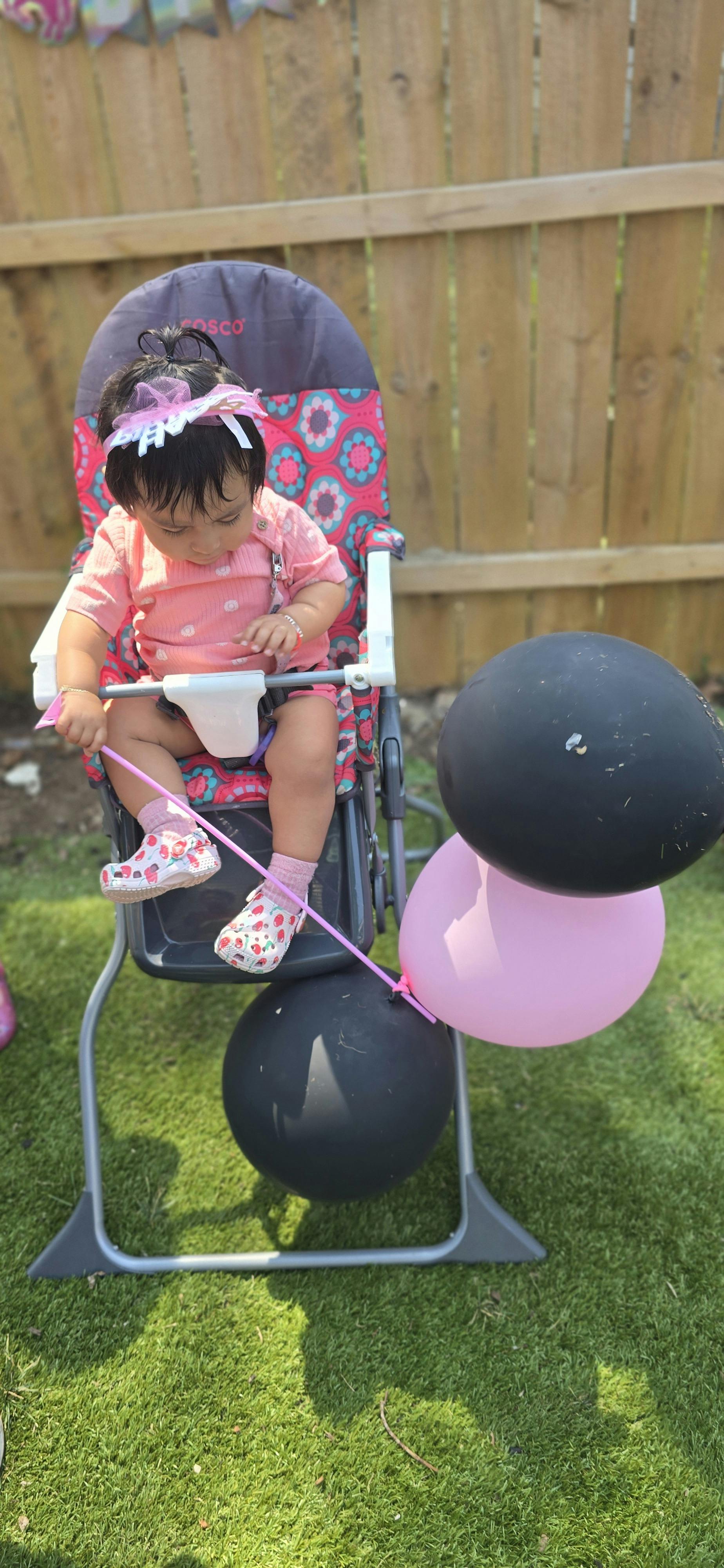 Child in a high chair holding a balloon string