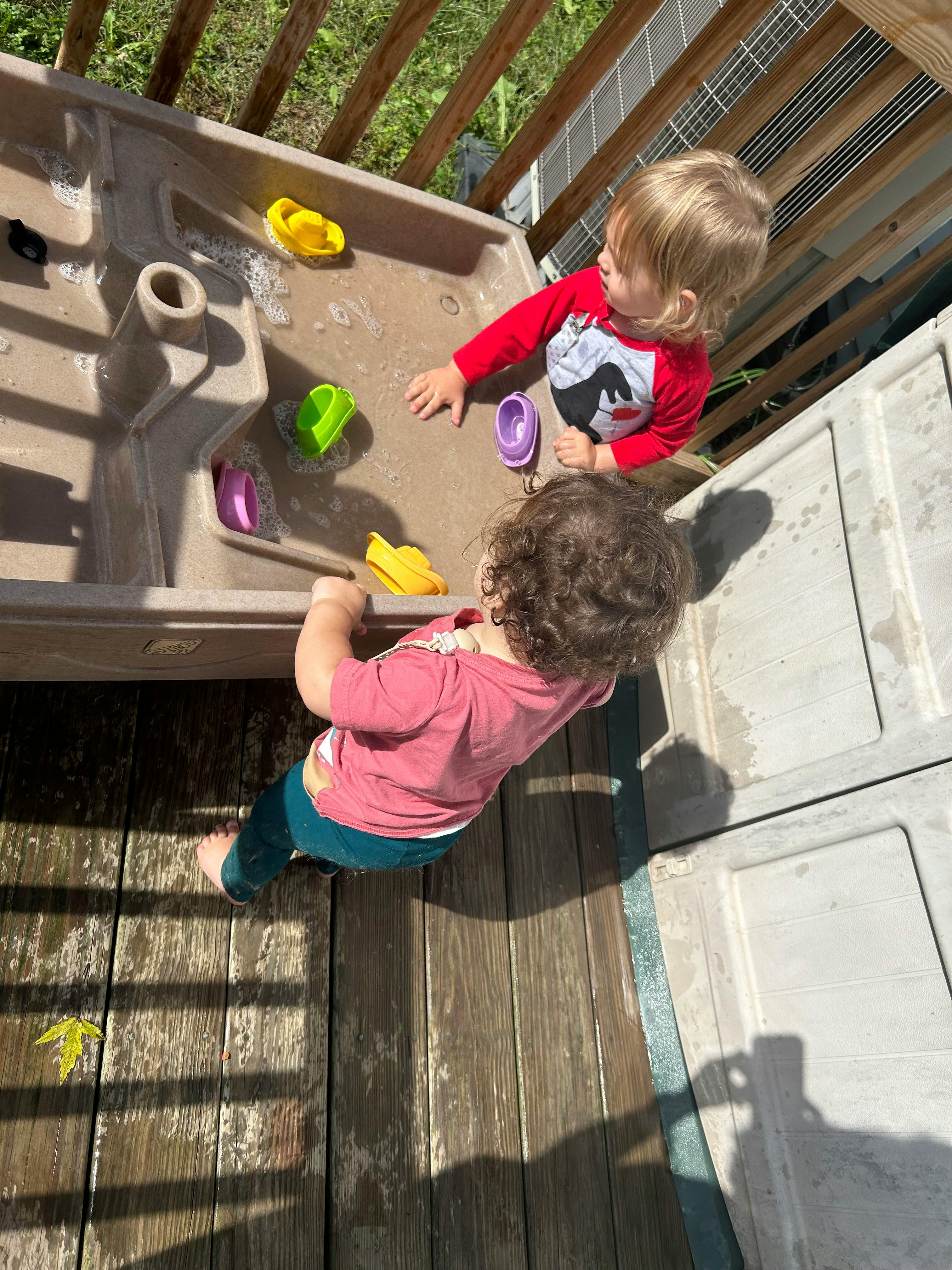 Two children playing with a water table