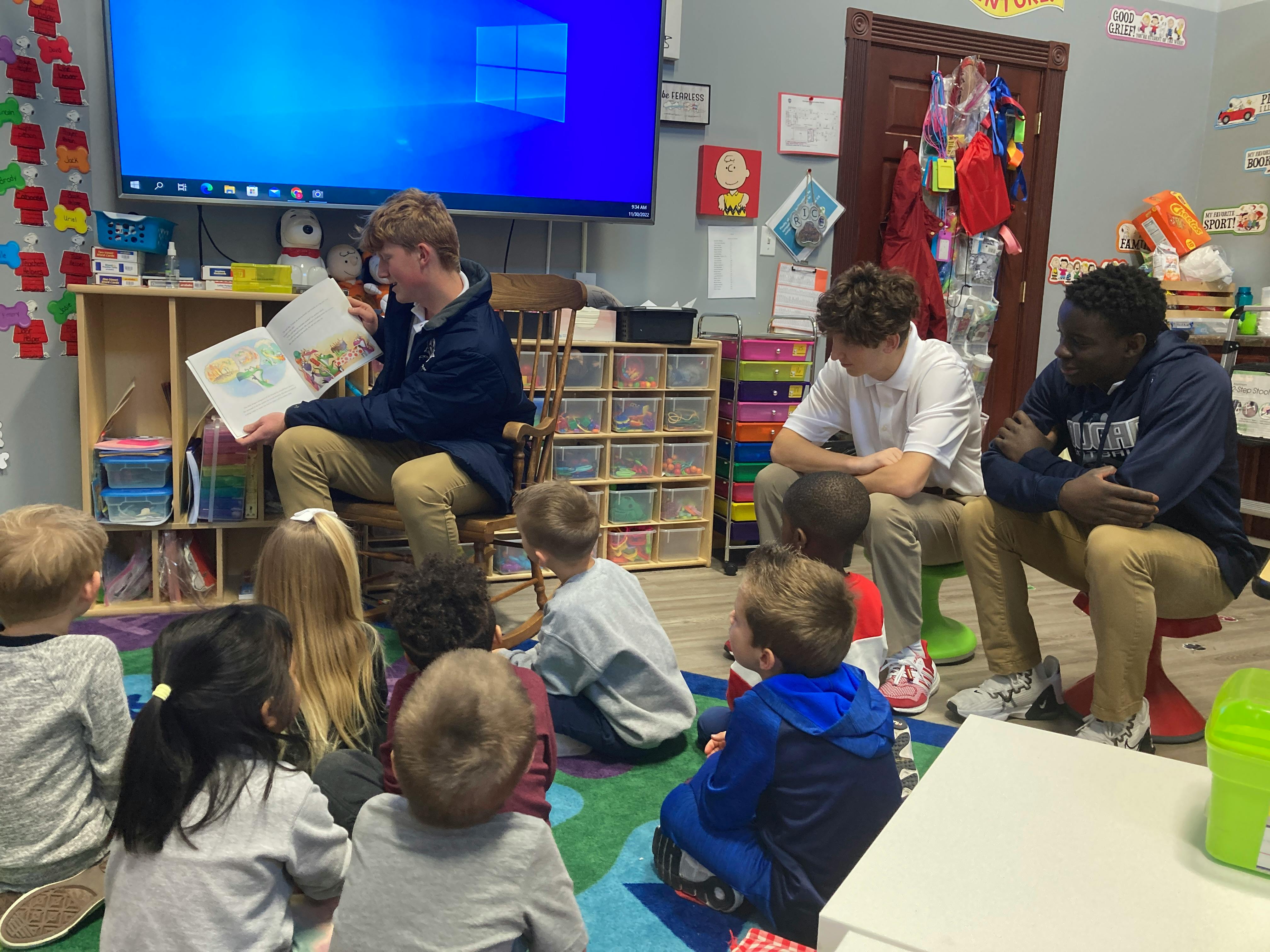 Person reading a book to a group of children in a classroom