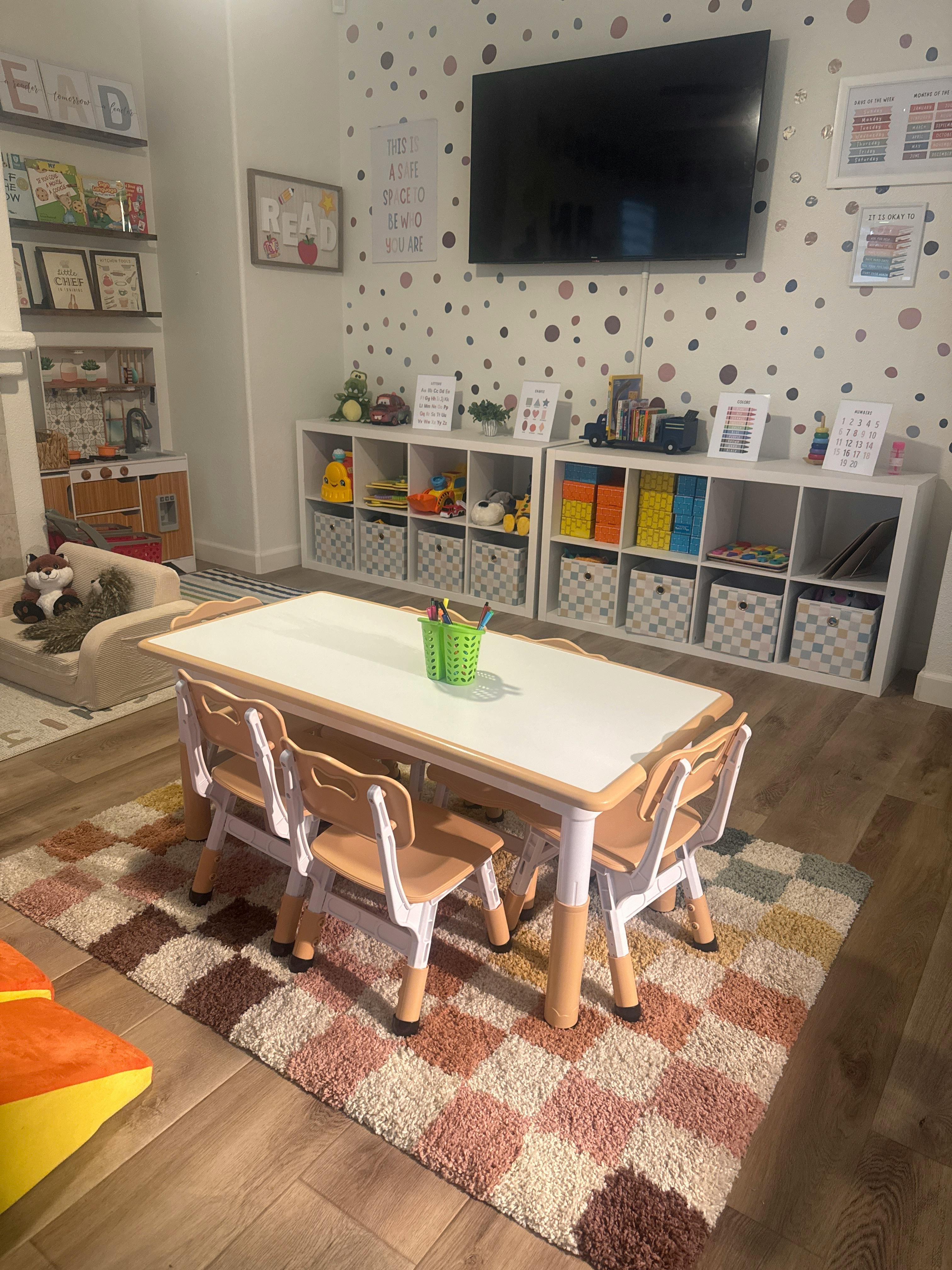 Children's play area with a small table and chairs, storage shelves, and wall decor