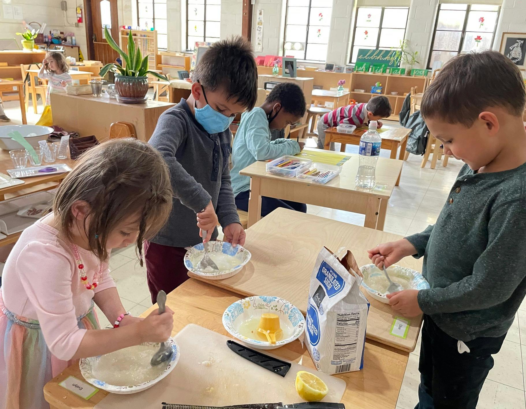 Children mixing ingredients at tables in a classroom