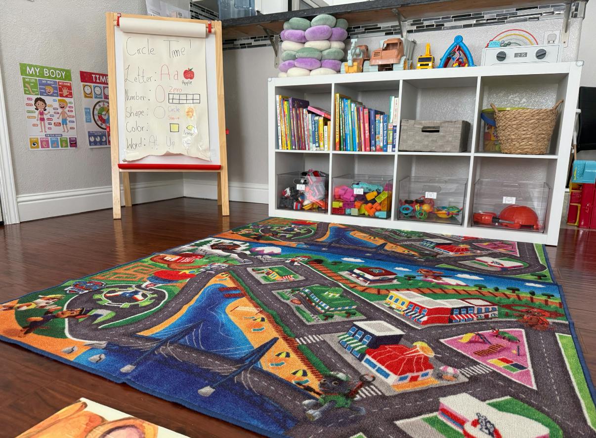 Playroom with a street rug, book shelf, and easel with circle time lesson