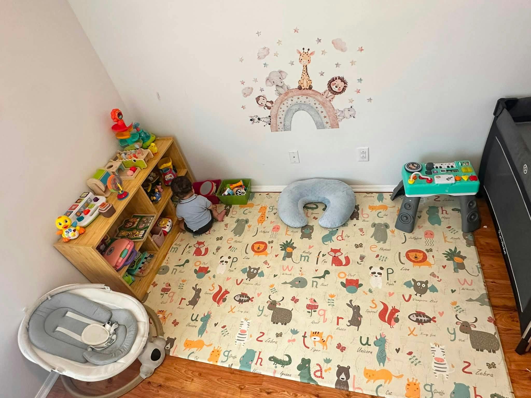 Child sitting on an alphabet play mat in a playroom