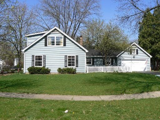 Light blue house with black shutters and a detached garage