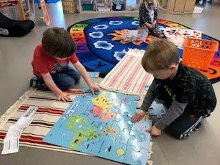 Two children playing with a puzzle on the floor