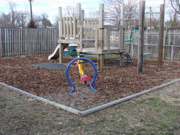 Playground with wooden structure, slide, swings, and a blue and yellow seesaw