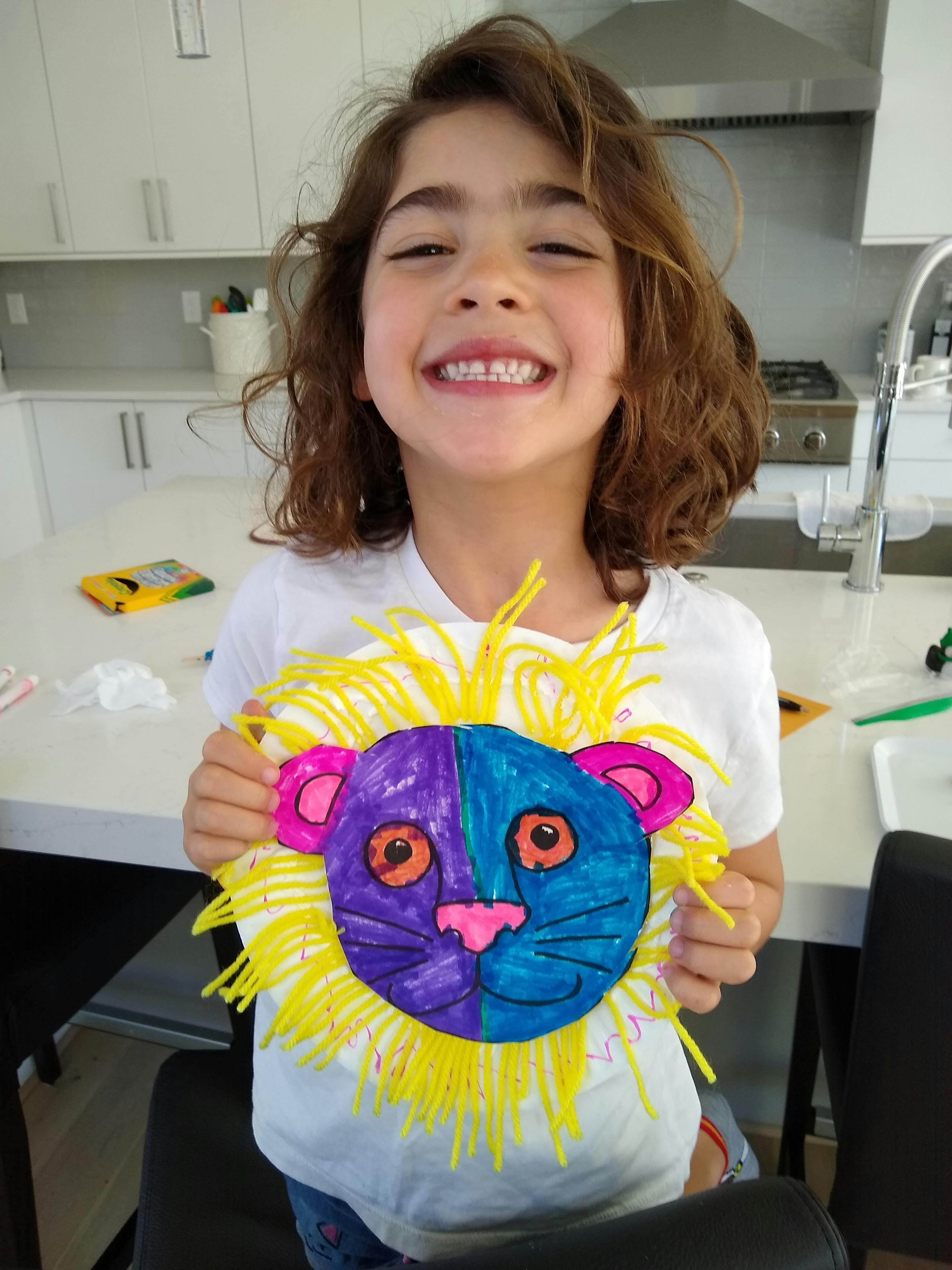 Child holding up a colorful paper lion craft