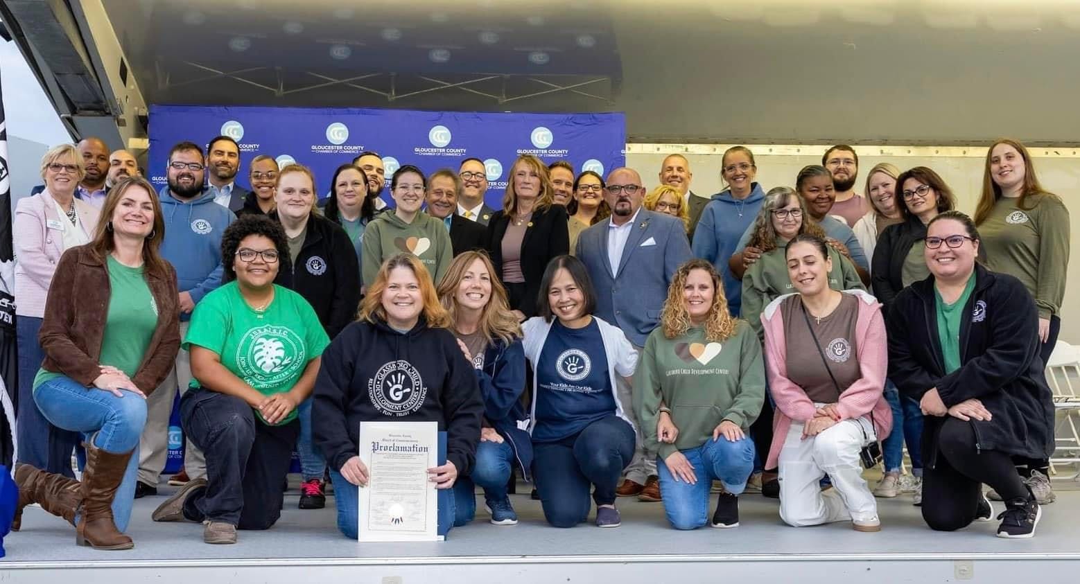 Group of people posing for a photo, some kneeling and holding a certificate