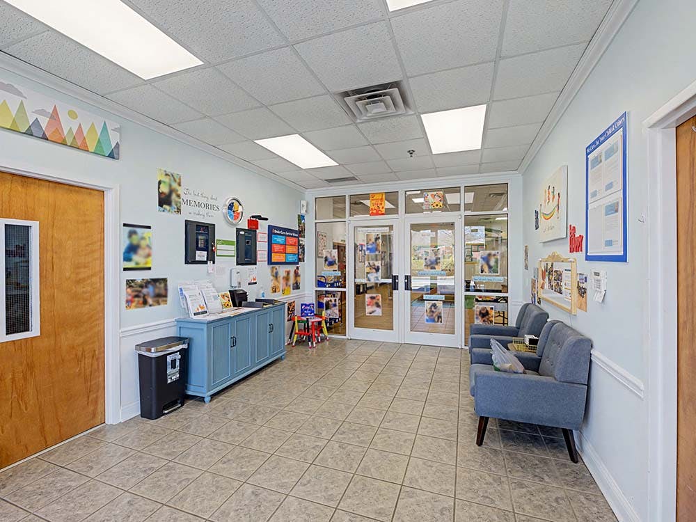 Lobby area with light blue walls, two gray chairs, and a blue cabinet