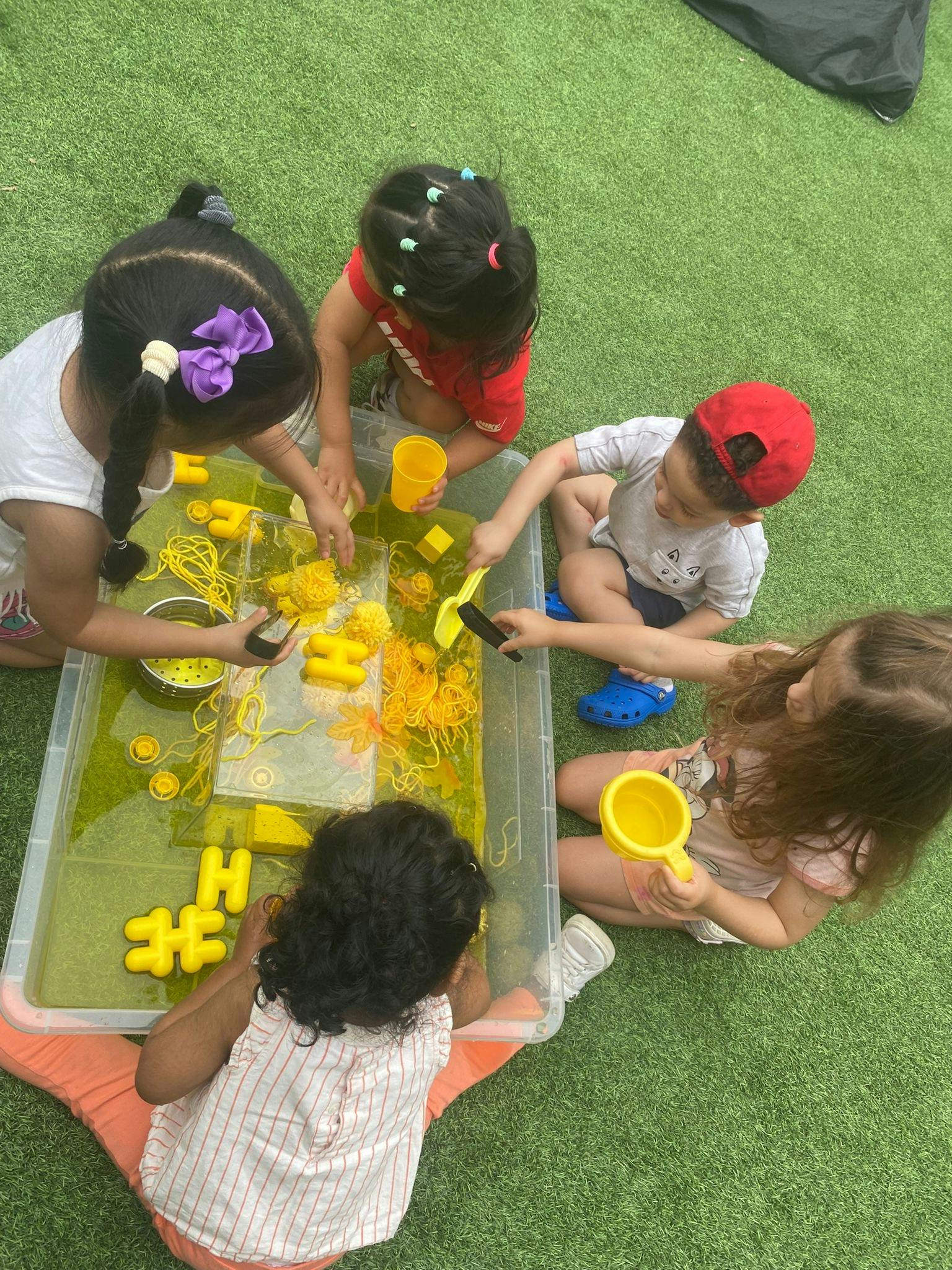 Children playing with water and toys in a sensory bin