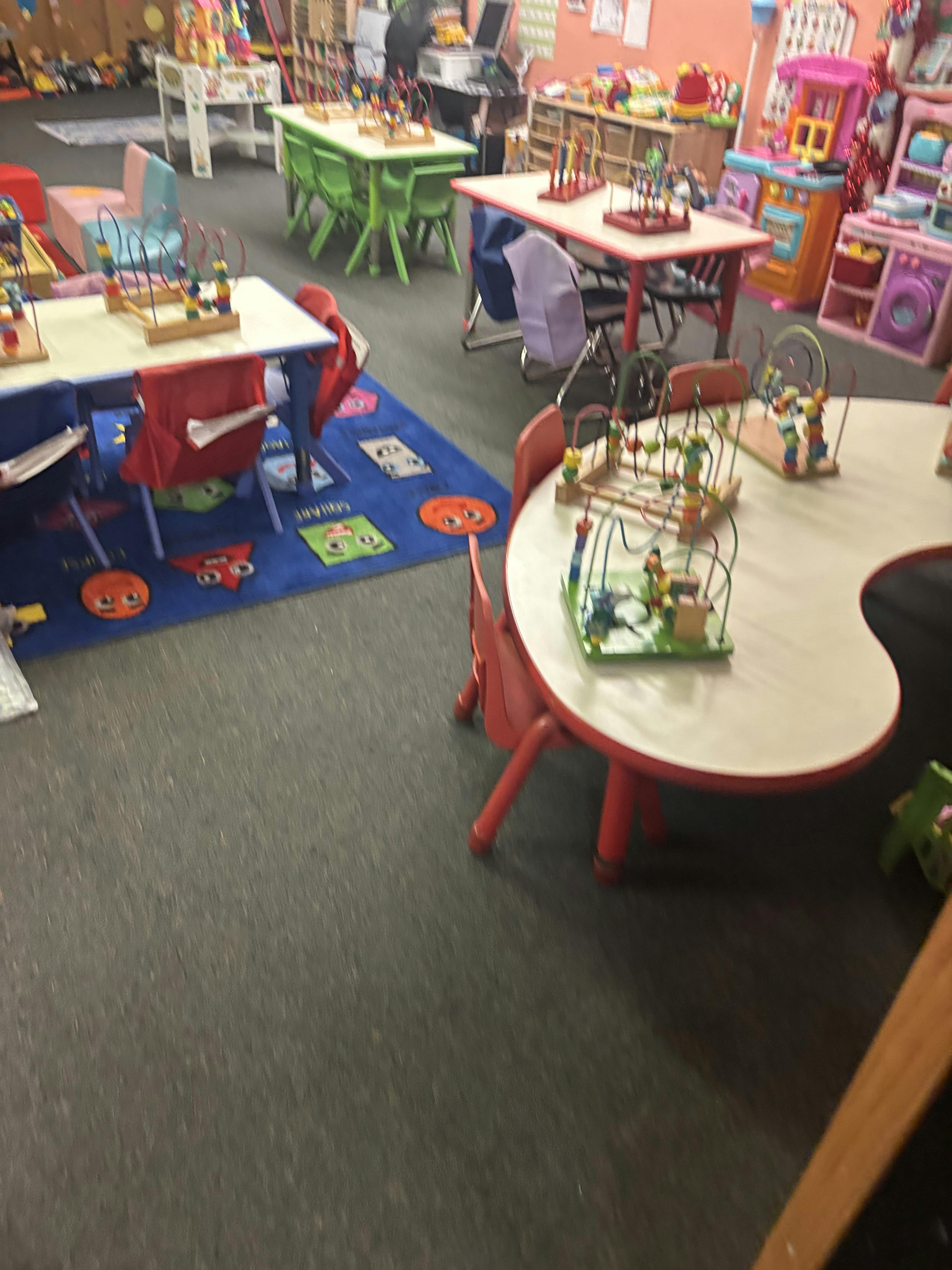 Colorful classroom with small tables, chairs, and bead maze toys
