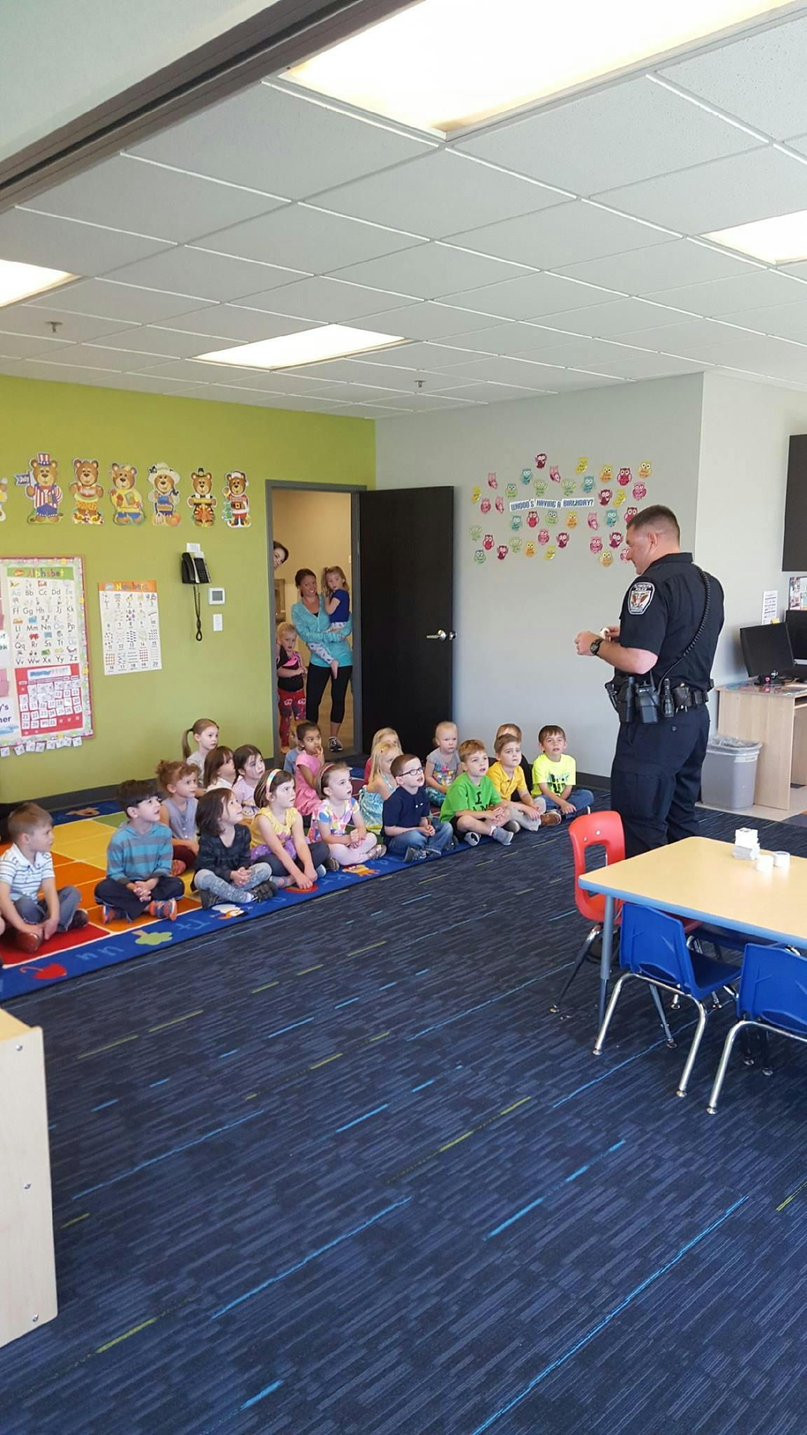 Police officer speaking to children sitting on a rug in a classroom