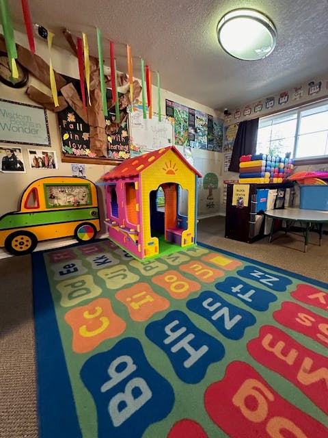 Playroom with a colorful playhouse, toy bus, and alphabet rug