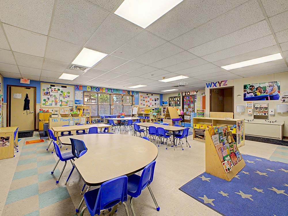 An empty classroom with small tables and chairs