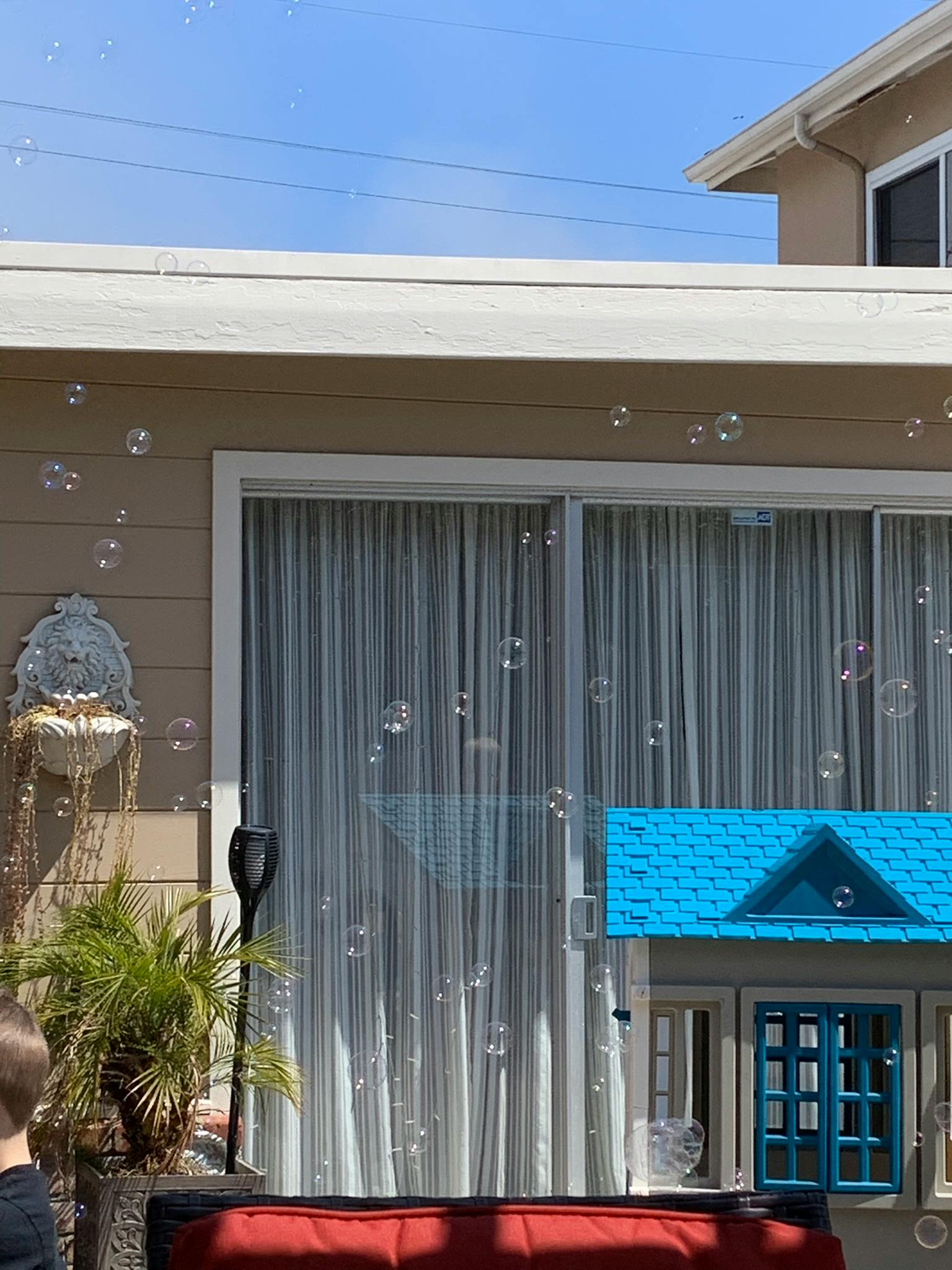 Bubbles floating in front of a house with a blue dollhouse