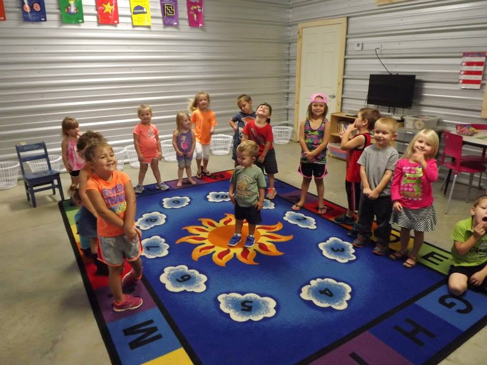 Group of children standing on a sun and cloud-themed rug in a room
