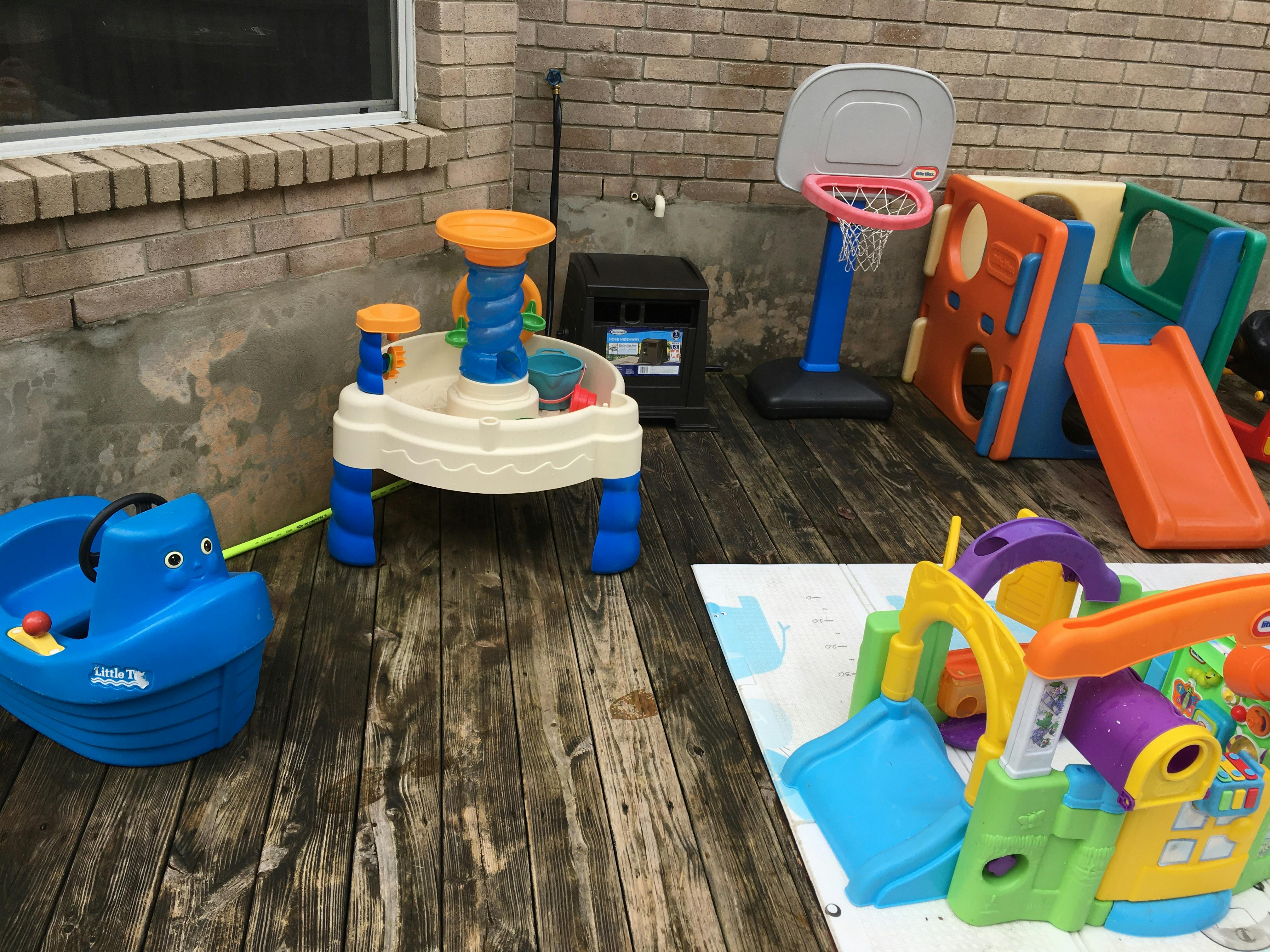 Outdoor play area with various colorful toys including a boat, water table, and slide