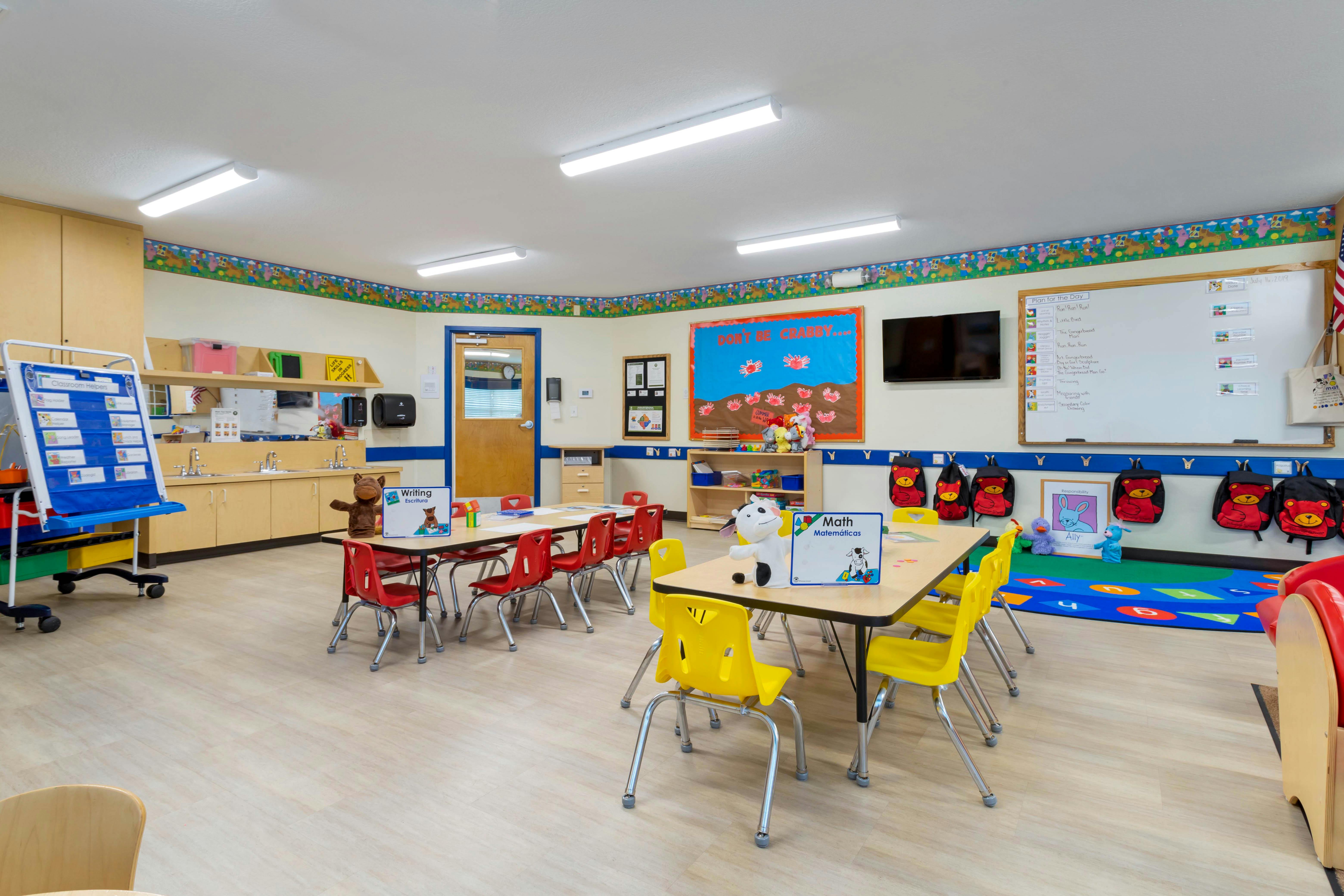 Classroom with tables, chairs, teaching materials, and a sink area