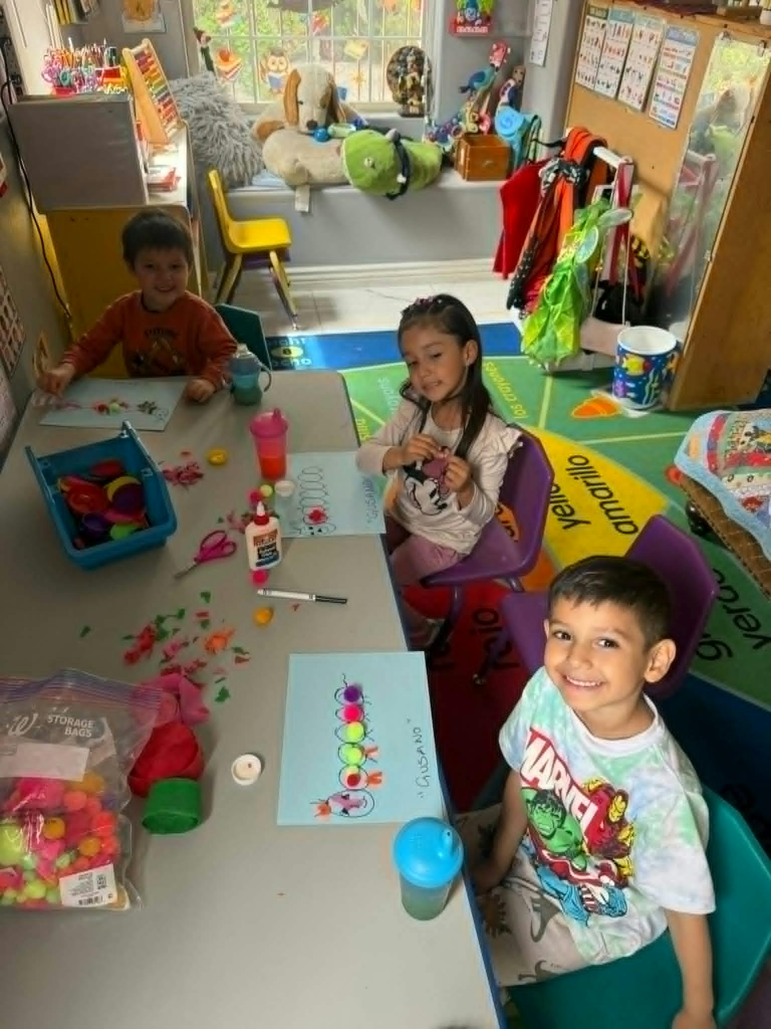 Three children sitting at a table with craft supplies