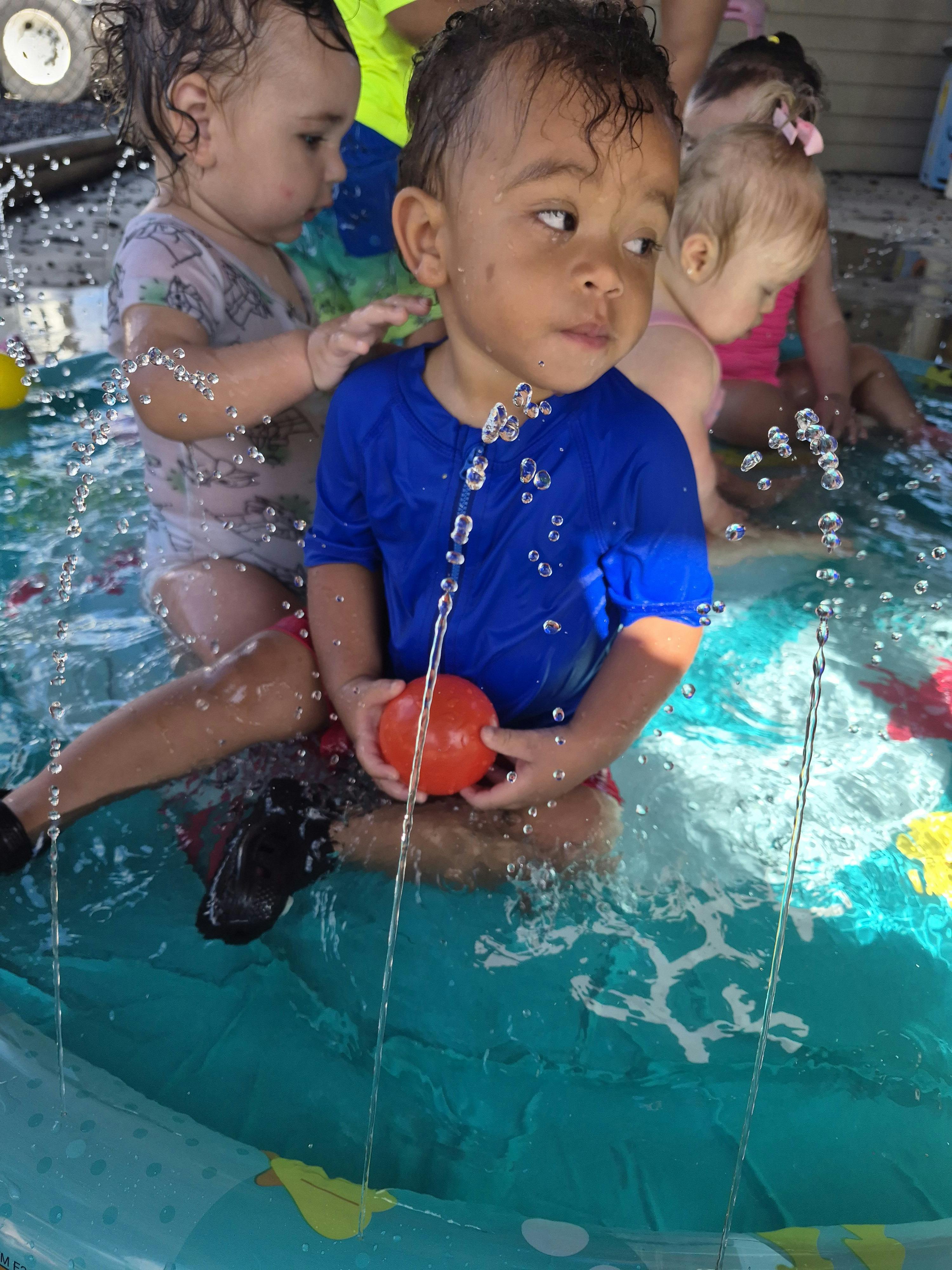 Children playing in a shallow inflatable pool with water jets