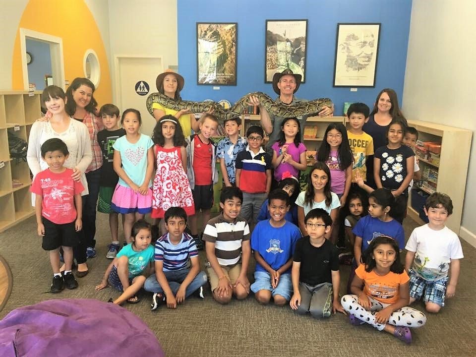 Group of adults and children posing for a photo in a classroom