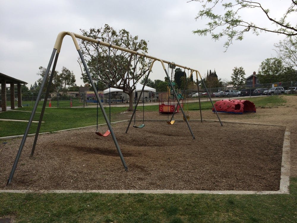 Empty swing set and red play tunnel on a playground