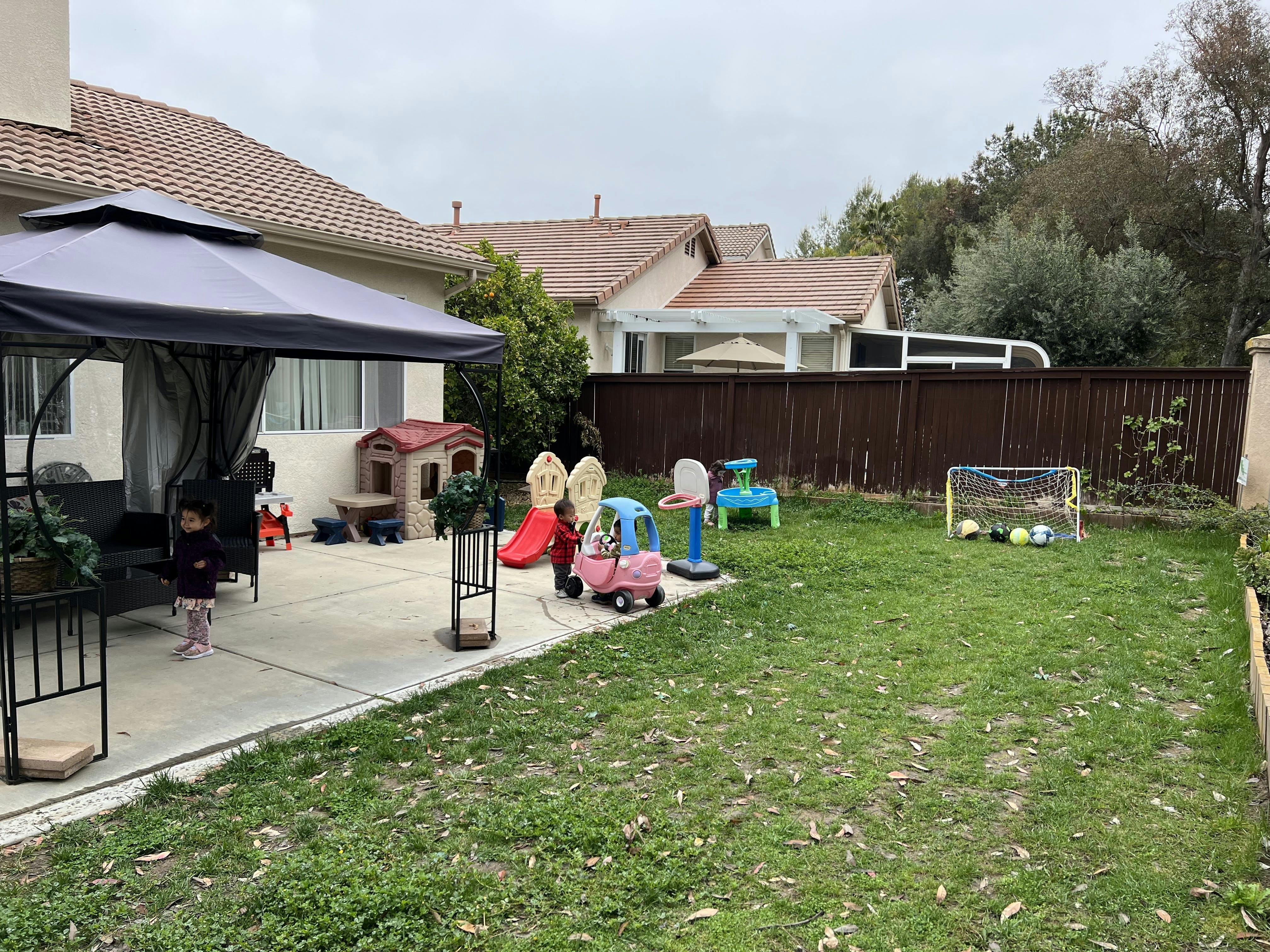Child on a patio with play equipment in a backyard