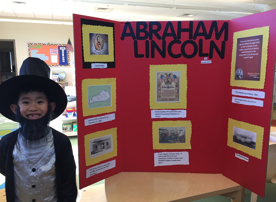 Child in Abraham Lincoln costume next to a red display board about Abraham Lincoln