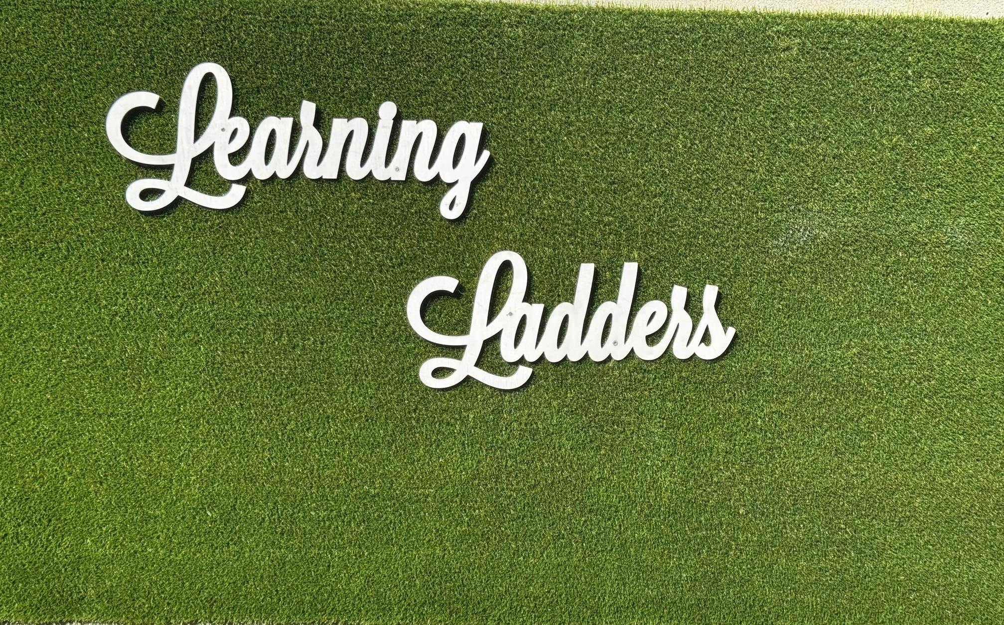 White cursive text "Learning Ladders" on a green textured background