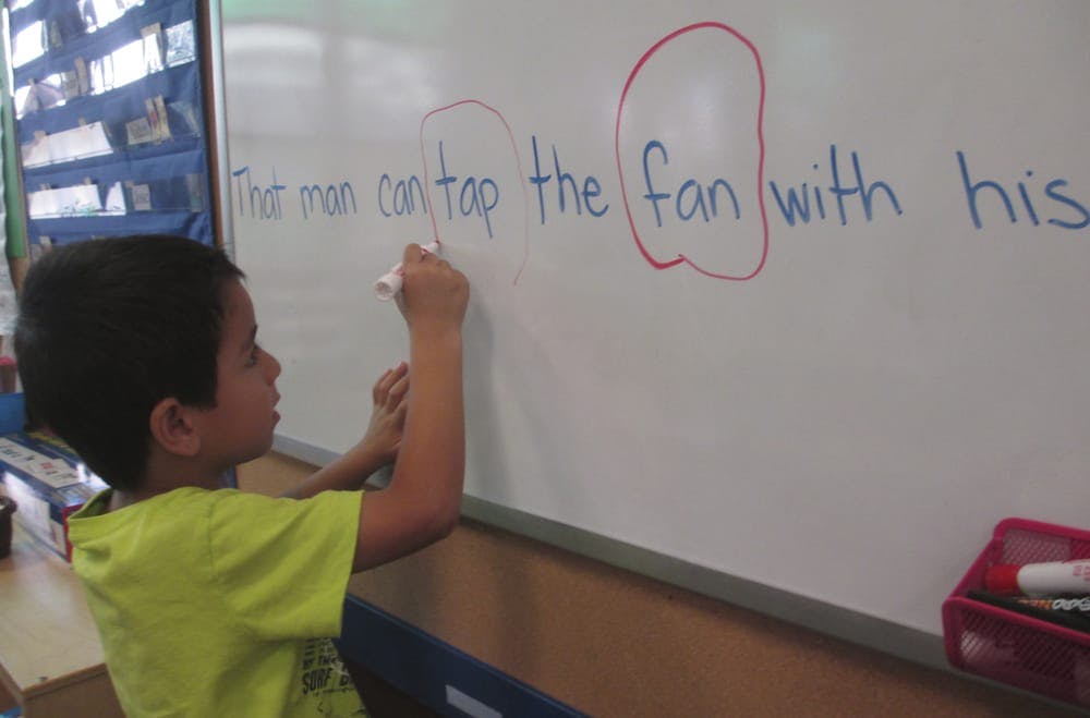 Child writing on a whiteboard in a classroom